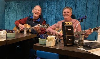 two members of folk club sitting down holding guitars
