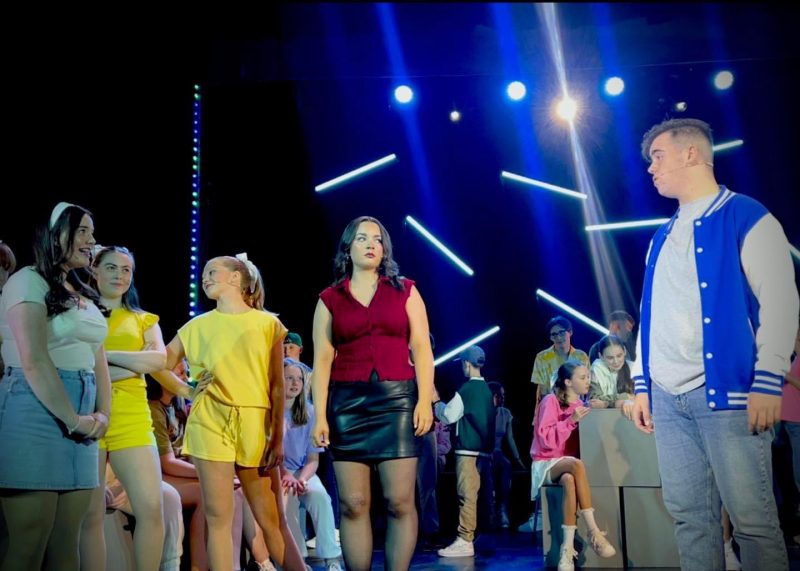 young people standing on a stage mid performance