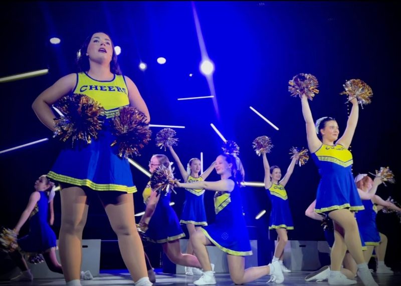 cast of cheerleaders performing on stage
