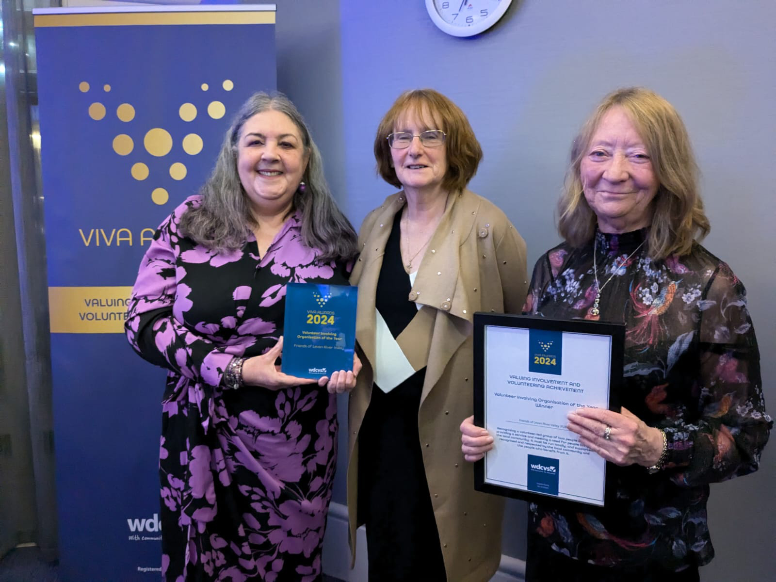 Three women standing with award